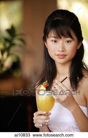 Young woman holding a drink, looking at camera View Large Photo Image Stock Image - Young woman holding a drink, looking at camera. Fotosearch