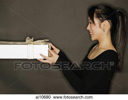 Young woman holding a gift, black background View Large Photo Image Stock Image - Young woman holding a gift, black background. Fotosearch