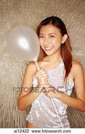 Young woman holding balloon, looking at camera View Large Photo Image Stock Image - Young woman holding balloon, looking at camera. Fotosearch