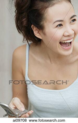 Young woman holding cellular phone, laughing View Large Photo Image Stock Photo - Young woman holding cellular phone, laughing. Fotosearch