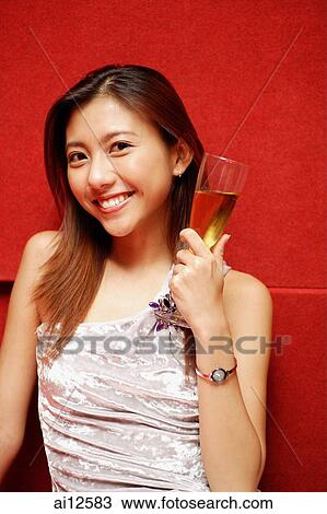 Young woman holding champagne glass, smiling at camera View Large Photo Image Stock Image - Young woman holding champagne glass, smiling at camera. Fotosearch