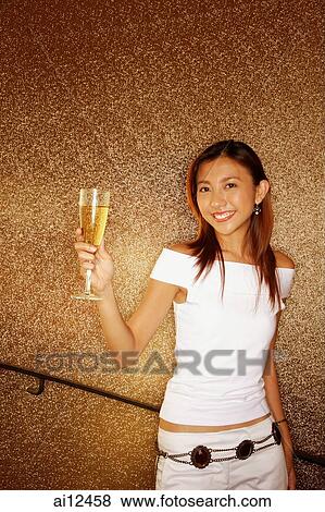 Young woman holding champagne glass, looking at camera View Large Photo Image Stock Photo - Young woman holding champagne glass, looking at camera. Fotosearch