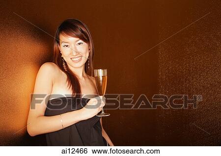 Young woman holding champagne glass, looking at camera View Large Photo Image Stock Photograph - Young woman holding champagne glass, looking at camera. Fotosearch