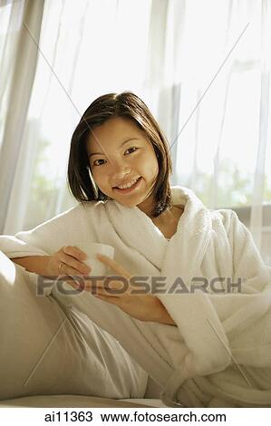 Young woman holding coffee cup, looking at camera View Large Photo Image Stock Image - Young woman holding coffee cup, looking at camera. Fotosearch