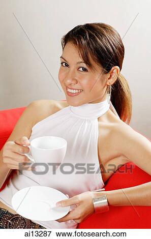 Young woman holding cup and saucer, looking at camera View Large Photo Image Stock Photo - Young woman holding cup and saucer, looking at camera. Fotosearch