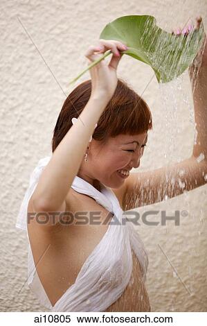 Young woman holding leaf, water cascading on her View Large Photo Image Stock Photography - Young woman holding leaf, water cascading on her. Fotosearch