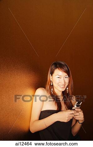 Picture - Young woman holding mobile phone, smiling. Fotosearch