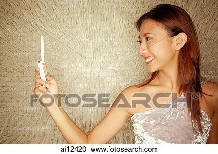 Young woman holding mobile phone, sideview View Large Photo Image Stock Image - Young woman holding mobile phone, sideview. Fotosearch