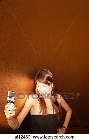 Young woman holding mobile phone, smiling View Large Photo Image Stock Image - Young woman holding mobile phone, smiling. Fotosearch