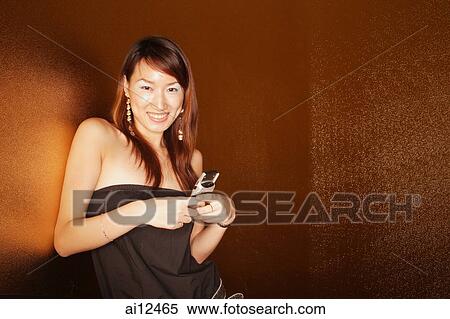Young woman holding mobile phone, looking at camera View Large Photo Image Stock Photography - Young woman holding mobile phone, looking at camera. Fotosearch