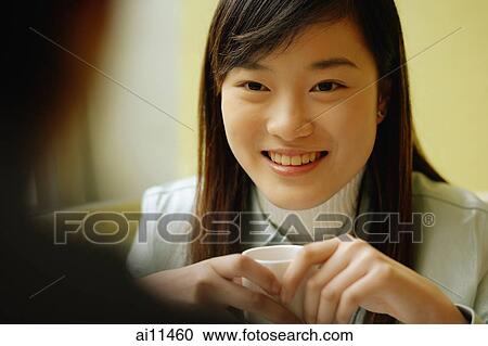 Young woman holding teacup, looking forward View Large Photo Image Stock Image - Young woman holding teacup, looking forward. Fotosearch