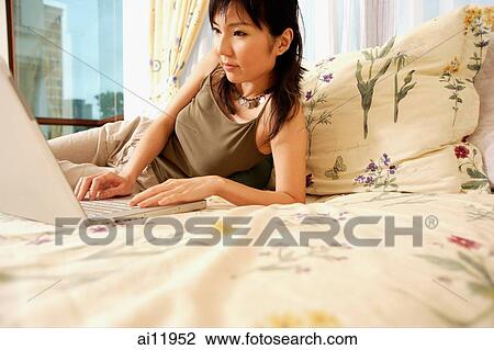 Young woman in bedroom using laptop. smiling View Large Photo Image Stock Image - Young woman in bedroom using laptop. smiling. Fotosearch