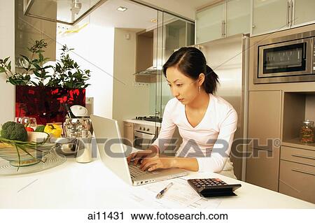 Young woman in kitchen, using laptop View Large Photo Image Stock Image - Young woman in kitchen, using laptop. Fotosearch