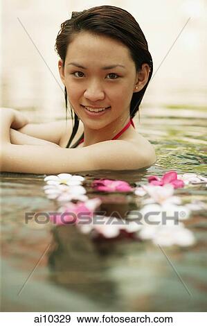 Stock Photo - Young woman in swimming pool, looking at camera, smiling. Fotosearch