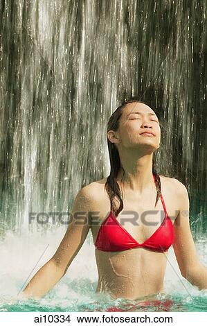 Young woman in swimming pool, water cascading on her, eyes closed View Large Photo Image Picture - Young woman in swimming pool, water cascading on her, eyes closed. Fotosearch