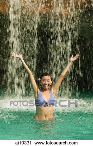 Young woman in swimming pool, water cascading on her View Large Photo Image Stock Image - Young woman in swimming pool, water cascading on her. Fotosearch