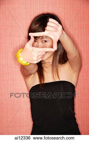 Stock Photograph - Young woman in tube top making hand sign, looking at camera. Fotosearch