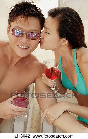 Stock Image - Young woman kissing man on cheek. Fotosearch