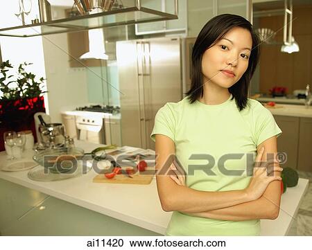 Young woman leaning on kitchen counter, looking at camera View Large Photo Image Stock Image - Young woman leaning on kitchen counter, looking at camera. Fotosearch