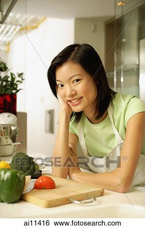 Young woman leaning on kitchen counter, smiling, looking at camera View Large Photo Image Stock Photograph - Young woman leaning on kitchen counter, smiling, looking at camera. Fotosearch