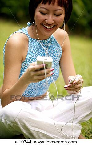 Young woman listening to personal stereo, looking down View Large Photo Image Picture - Young woman listening to personal stereo, looking down. Fotosearch