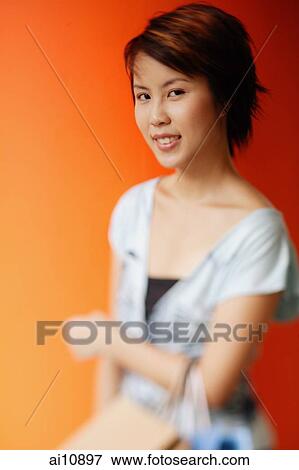 Stock Photo - Young woman looking at camera, carrying shopping bags. Fotosearch