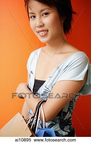 Young woman looking at camera, carrying shopping bags View Large Photo Image Stock Photography - Young woman looking at camera, carrying shopping bags. Fotosearch