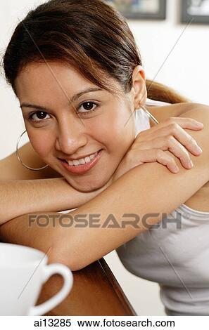 Stock Photography - Young woman looking at camera, head on arm. Fotosearch