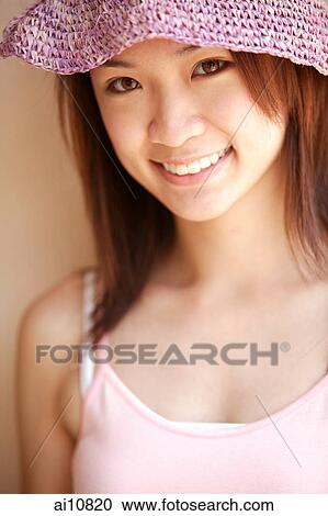 Stock Image - Young woman looking at camera, wearing hat. Fotosearch