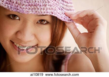 Stock Photo - Young woman looking at camera, wearing hat. Fotosearch