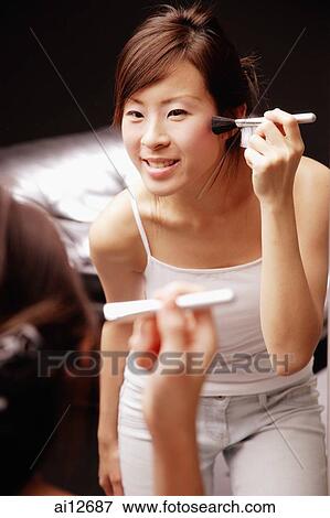Young woman looking at mirror applying blusher with brush View Large Photo Image Stock Photo - Young woman looking at mirror applying blusher with brush. Fotosearch