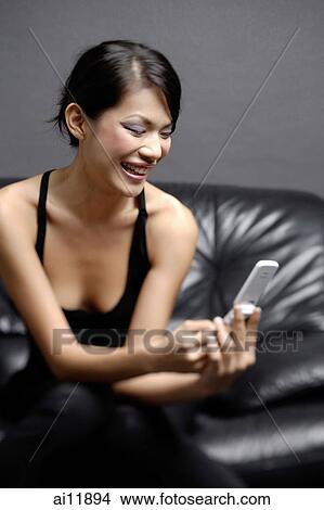 Picture -  Young woman looking at mobile phone. Fotosearch