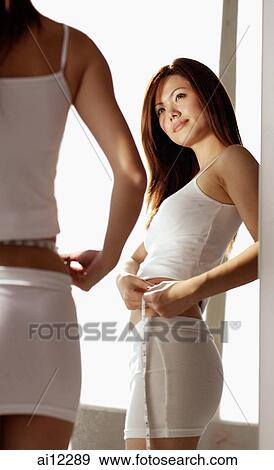 Young woman, looking at reflection, holding measuring tape View Large Photo Image Stock Photo - Young woman, looking at reflection, holding measuring tape. Fotosearch