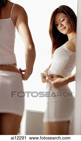Young woman looking at tape measure around her waist View Large Photo Image Stock Image - Young woman looking at tape measure around her waist. Fotosearch
