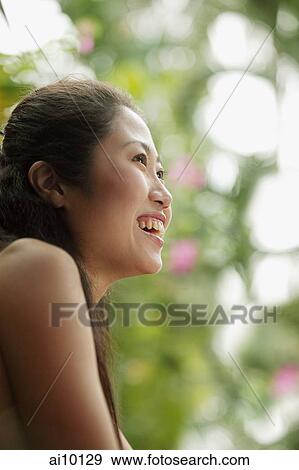 Stock Photo - Young woman looking away, smiling.. Fotosearch