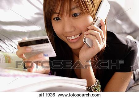 Young woman looking credit card, using phone View Large Photo Image Stock Photograph - Young woman looking credit card, using phone. Fotosearch
