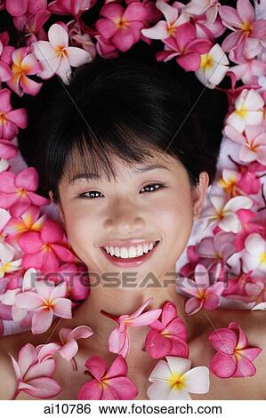 Young woman lying down amidst flowers, looking at camera View Large Photo Image Stock Photograph - Young woman lying down amidst flowers, looking at camera. Fotosearch