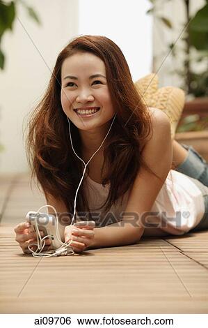 Young woman lying down, listening to music View Large Photo Image Stock Photograph - Young woman lying down, listening to music. Fotosearch