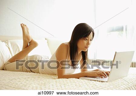 Young woman lying down on her front, using laptop View Large Photo Image Stock Photo - Young woman lying down on her front, using laptop. Fotosearch
