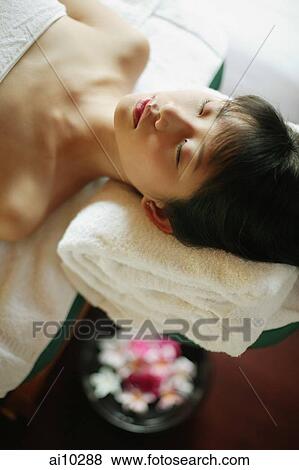 Young woman lying down on massage table View Large Photo Image Stock Photo - Young woman lying down on massage table. Fotosearch