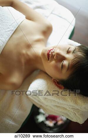 Young woman lying down on massage table View Large Photo Image Stock Photo - Young woman lying down on massage table. Fotosearch