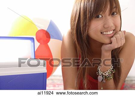 Young woman lying on floor, hand on chin, drink cooler next to her View Large Photo Image Picture - Young woman lying on floor, hand on chin, drink cooler next to her. Fotosearch