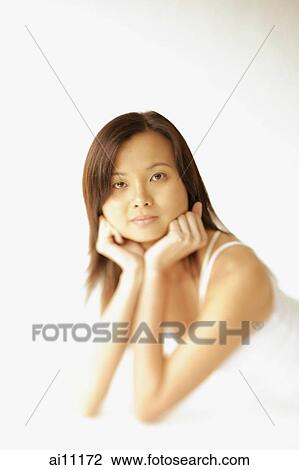 Young woman lying on floor, hands on chin, looking at camera View Large Photo Image Stock Image - Young woman lying on floor, hands on chin, looking at camera. Fotosearch