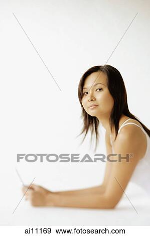 Young woman lying on floor, holding mobile phone, looking at camera View Large Photo Image Stock Photo - Young woman lying on floor, holding mobile phone, looking at camera. Fotosearch