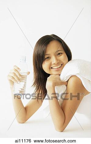 Young woman lying on floor, holding water bottle, smiling at camera View Large Photo Image Stock Photograph - Young woman lying on floor, holding water bottle, smiling at camera. Fotosearch