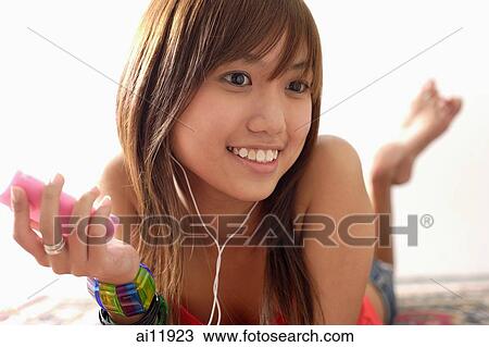 Young woman lying on floor, listening to MP3 player View Large Photo Image Stock Image - Young woman lying on floor, listening to MP3 player. Fotosearch