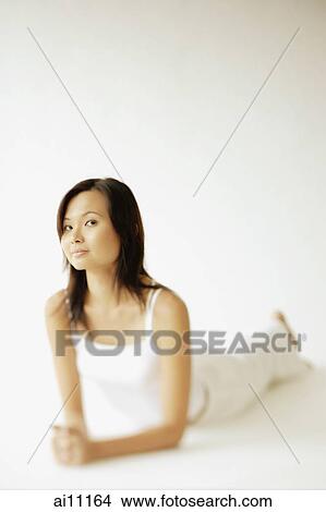 Young woman lying on floor, looking at camera View Large Photo Image Picture - Young woman lying on floor, looking at camera. Fotosearch