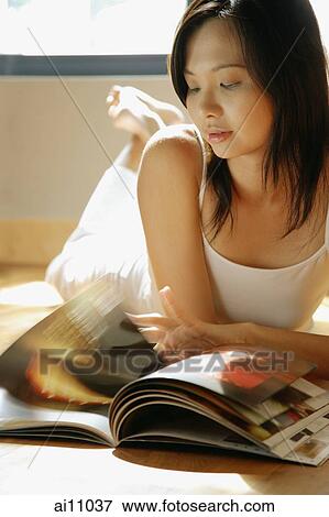Young woman lying on floor reading magazine. View Large Photo Image Stock Photo - Young woman lying on floor reading magazine.. Fotosearch