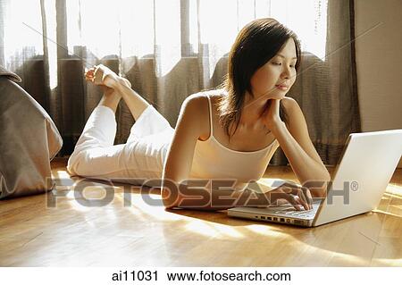 Young woman lying on floor, using laptop View Large Photo Image Stock Image - Young woman lying on floor, using laptop. Fotosearch