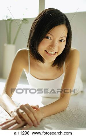 Young woman lying on front, looking at camera View Large Photo Image Stock Photo - Young woman lying on front, looking at camera. Fotosearch